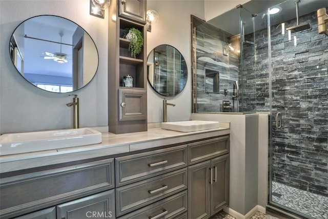 full bath with double vanity, a ceiling fan, a stall shower, and a sink