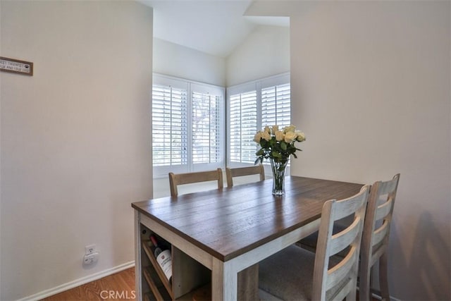 dining space with baseboards, wood finished floors, and lofted ceiling