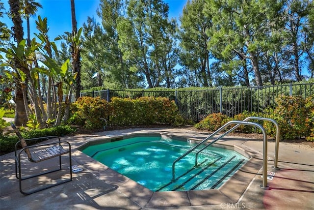 view of swimming pool with a hot tub and fence
