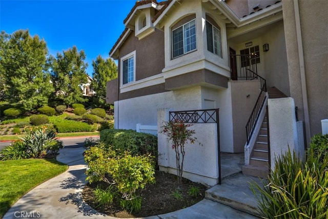 view of side of home featuring stairs and stucco siding
