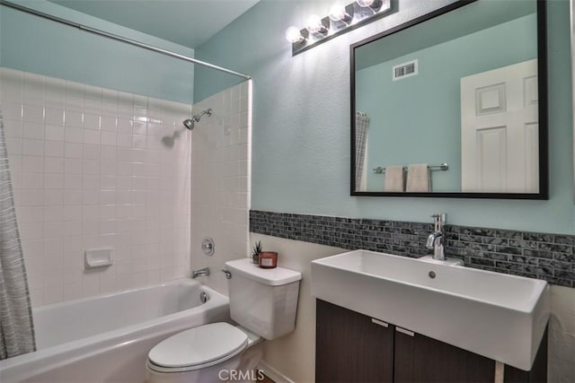 bathroom with visible vents, shower / bath combination with curtain, toilet, tile walls, and a sink