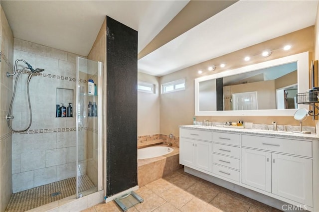 full bathroom featuring a sink, double vanity, tile patterned floors, a shower stall, and a garden tub