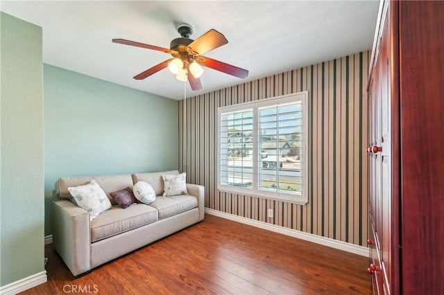 interior space with baseboards, a ceiling fan, wallpapered walls, and wood finished floors