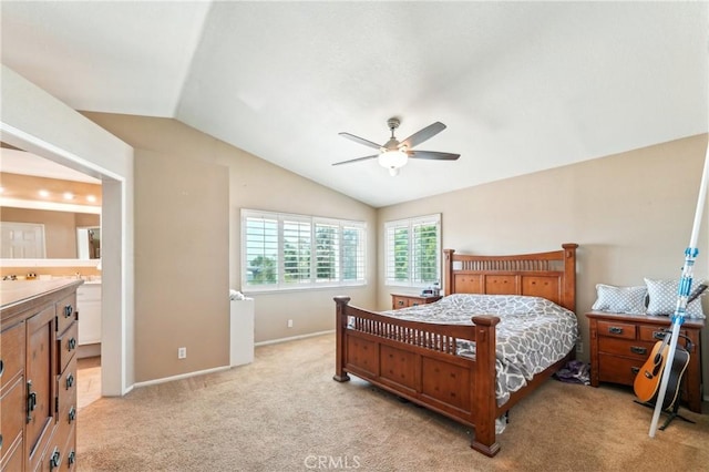 bedroom featuring light colored carpet, a ceiling fan, baseboards, ensuite bathroom, and vaulted ceiling