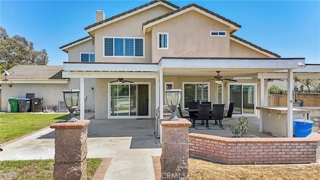 rear view of house featuring ceiling fan, a patio area, and stucco siding