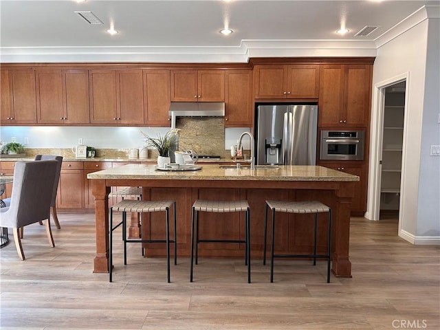 24 Flowerstalk, Irvine, CA 92618 - kitchen with appliances with stainless steel finishes, a sink, brown cabinetry, a kitchen breakfast bar, and crown molding