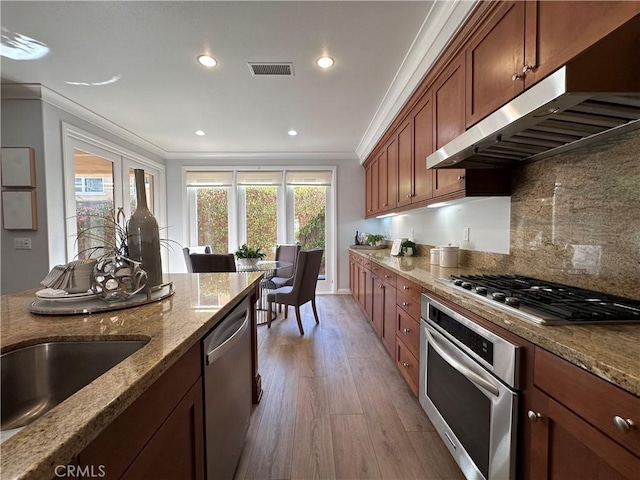 24 Flowerstalk, Irvine, CA 92618 - kitchen with stainless steel appliances, crown molding, under cabinet range hood, stone countertops, and light wood finished floors