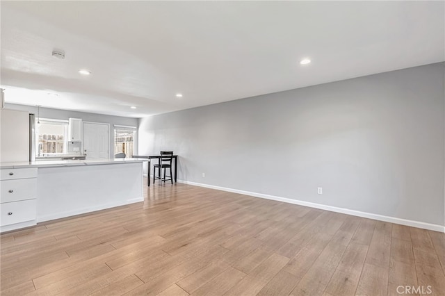 unfurnished living room featuring recessed lighting, light wood finished floors, and baseboards