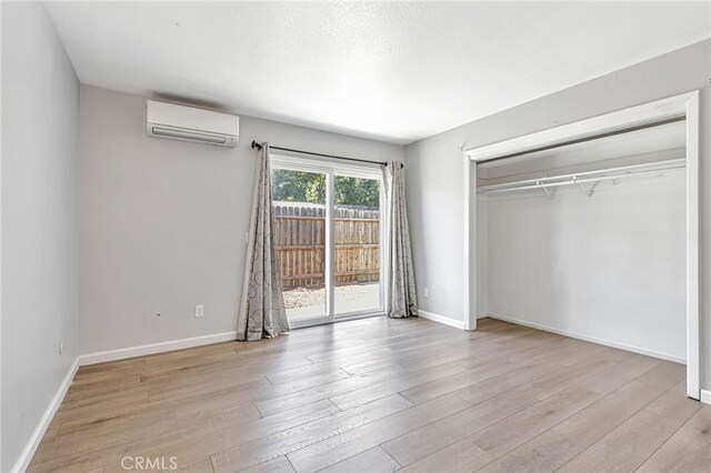 6633 Plymouth Rd, Stockton, CA 95207 - unfurnished bedroom featuring a wall mounted air conditioner, access to outside, wood finished floors, a closet, and baseboards