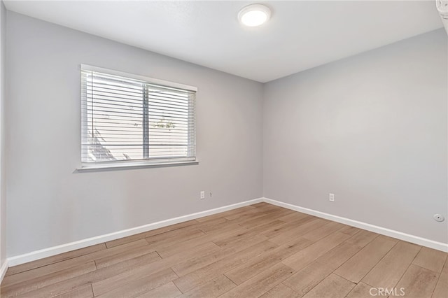 empty room with baseboards and light wood-type flooring