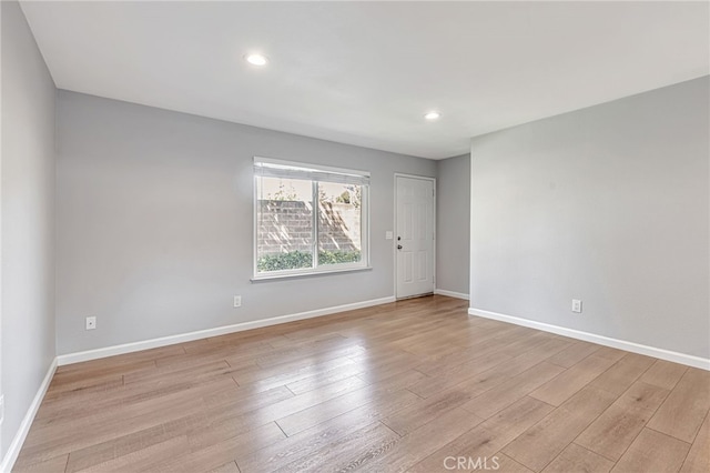 empty room with light wood-style floors, baseboards, and recessed lighting