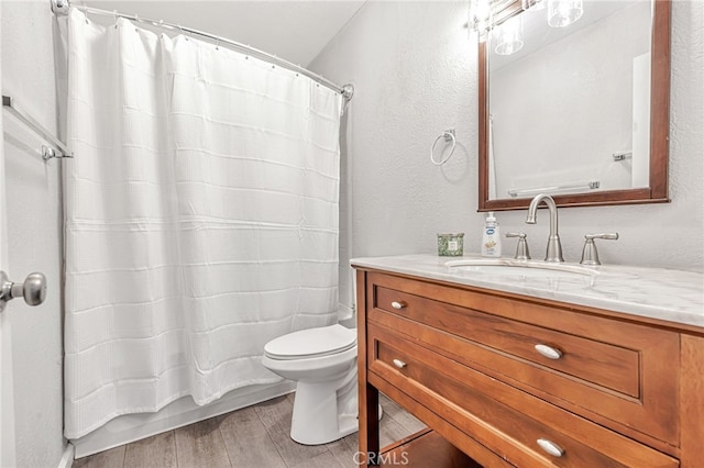 full bathroom featuring vanity, a textured wall, toilet, and wood finished floors