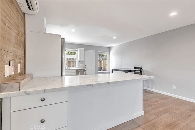 kitchen featuring white cabinets, a peninsula, recessed lighting, and light wood-style floors