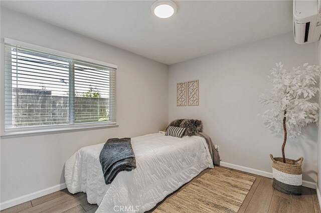 6633 Plymouth Rd, Stockton, CA 95207 - bedroom featuring wood finished floors, baseboards, and an AC wall unit