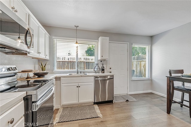 6633 Plymouth Rd, Stockton, CA 95207 - kitchen featuring stainless steel appliances, a sink, light wood finished floors, and white cabinetry