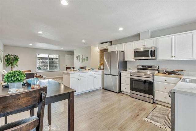 6633 Plymouth Rd, Stockton, CA 95207 - kitchen featuring appliances with stainless steel finishes, a wall unit AC, white cabinetry, light wood-style flooring, and recessed lighting