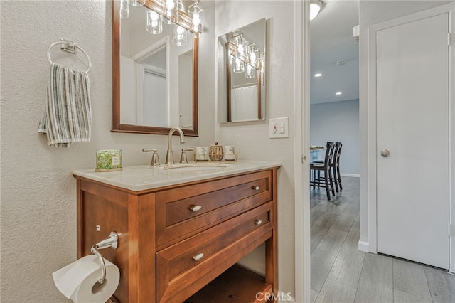 6633 Plymouth Rd, Stockton, CA 95207 - bathroom with vanity, a textured wall, wood finished floors, and recessed lighting