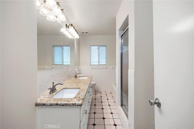 full bath with visible vents, tile patterned flooring, tile walls, a sink, and a shower with shower door