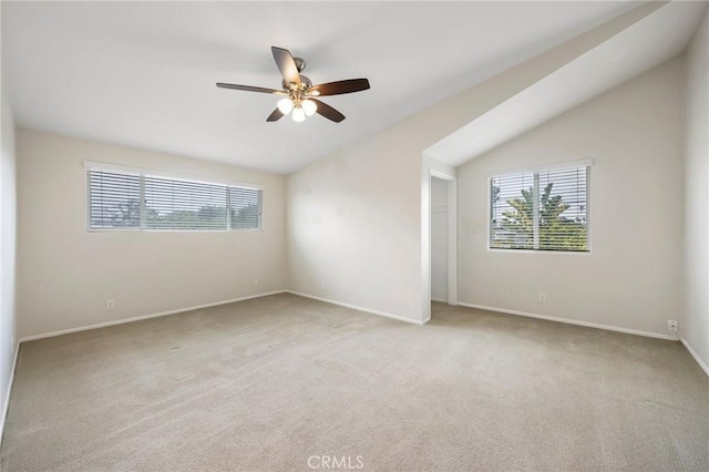 spare room with lofted ceiling, a wealth of natural light, and light carpet