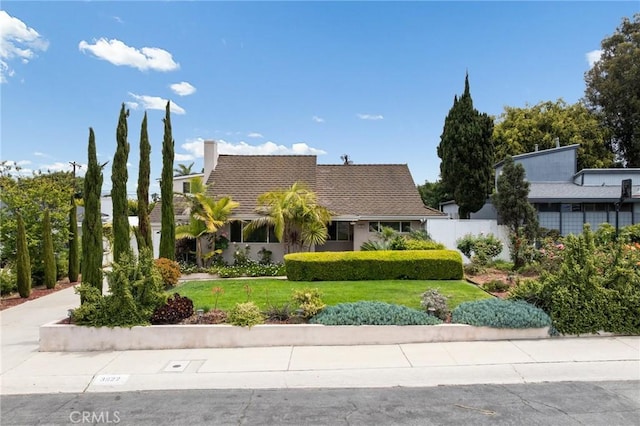 view of front of house featuring fence, a front yard, and a chimney