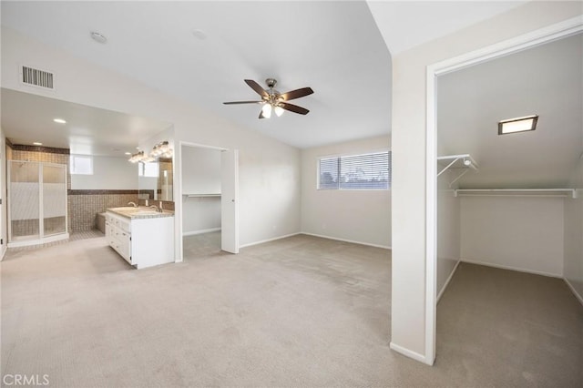 unfurnished bedroom featuring light colored carpet, ceiling fan, visible vents, and a sink