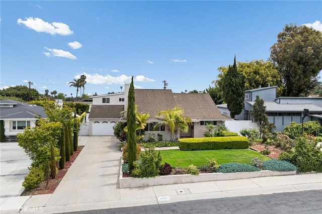 view of front of house with fence, an attached garage, driveway, and a front yard