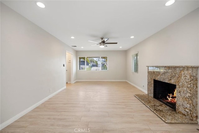 unfurnished living room featuring light wood-style floors, recessed lighting, ceiling fan, and a premium fireplace