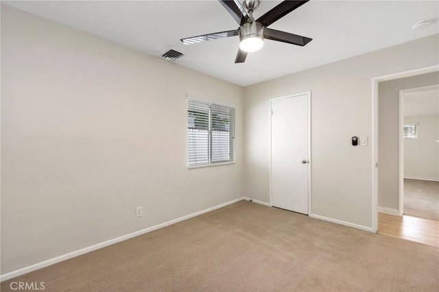 unfurnished bedroom with visible vents, a ceiling fan, baseboards, and light carpet