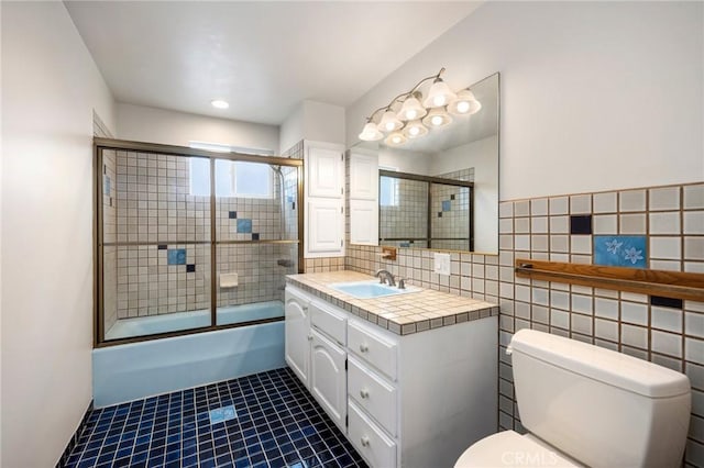 full bathroom with tile walls, tile patterned floors, vanity, toilet, and shower / bath combination with glass door