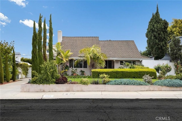 view of front of house with fence, a chimney, and concrete driveway