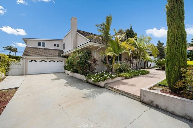 view of home's exterior featuring concrete driveway, an attached garage, a chimney, and stucco siding