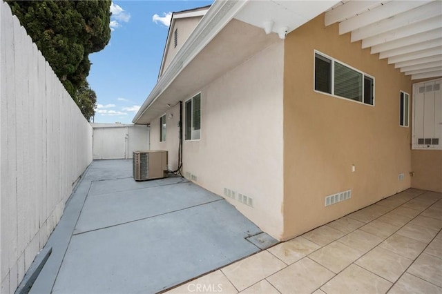 view of home's exterior with fence, a patio, stucco siding, central AC unit, and crawl space