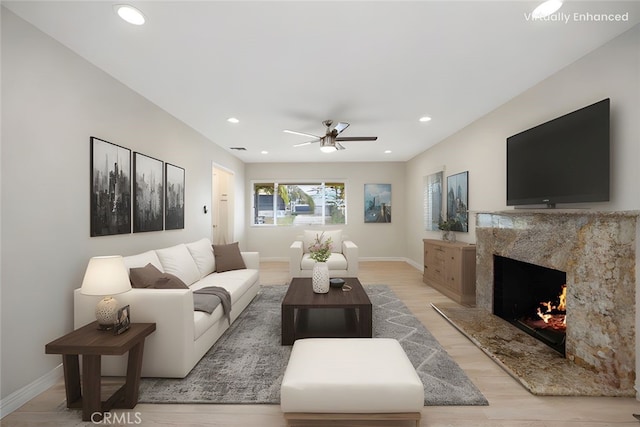 living area featuring light wood-style floors, a ceiling fan, baseboards, recessed lighting, and a high end fireplace