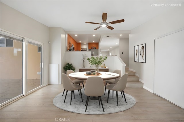 dining space with light wood-style floors, a ceiling fan, visible vents, and stairway