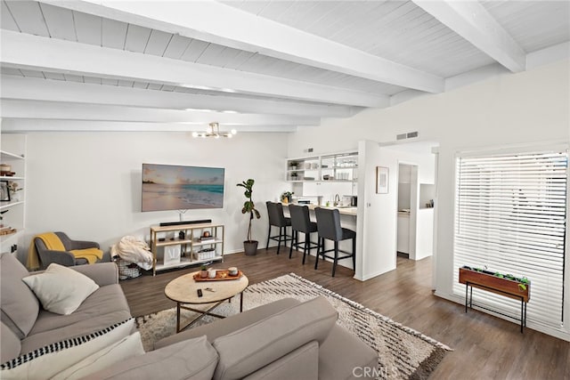 living area with visible vents, wood finished floors, baseboards, beamed ceiling, and a notable chandelier