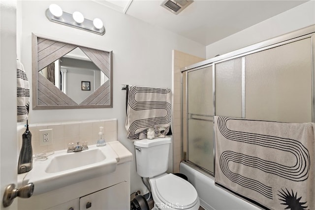 full bath with visible vents, vanity, toilet, shower / bath combination with glass door, and tasteful backsplash