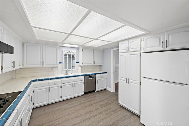 kitchen with tile counters, freestanding refrigerator, light wood-style flooring, and dishwasher