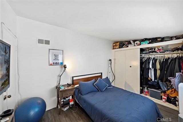 bedroom featuring visible vents, baseboards, wood finished floors, and a closet