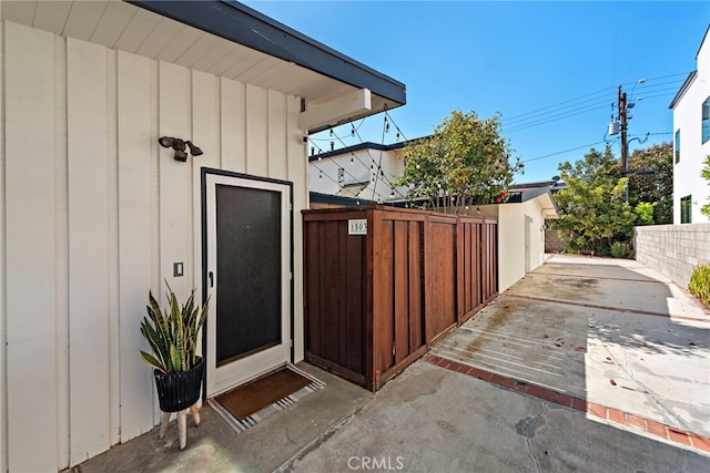 doorway to property with a gate, board and batten siding, and fence
