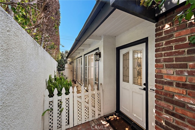 property entrance with stucco siding and fence