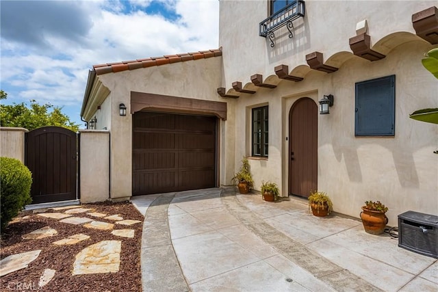 21 Alexa Ln, Ladera Ranch, CA 92694 - view of exterior entry with a gate, driveway, an attached garage, and stucco siding