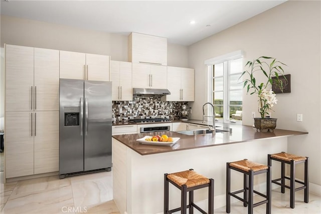 21 Alexa Ln, Ladera Ranch, CA 92694 - kitchen with appliances with stainless steel finishes, a kitchen breakfast bar, a peninsula, under cabinet range hood, and decorative backsplash
