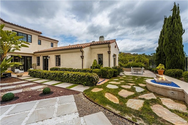 21 Alexa Ln, Ladera Ranch, CA 92694 - back of property with a fire pit, a chimney, a patio area, a tiled roof, and stucco siding
