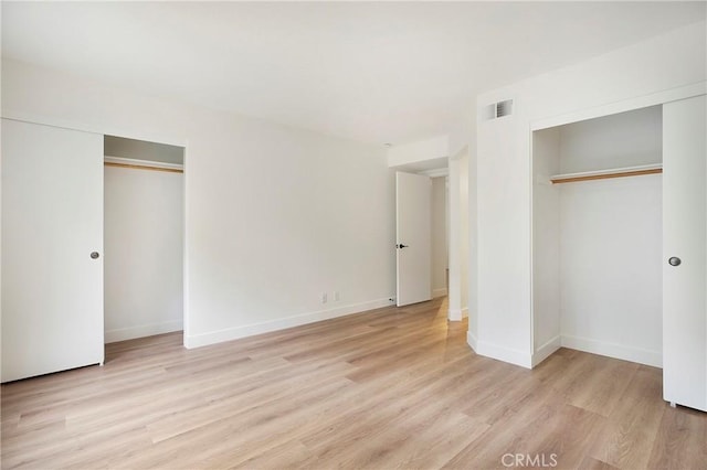 unfurnished bedroom featuring baseboards, visible vents, and light wood finished floors
