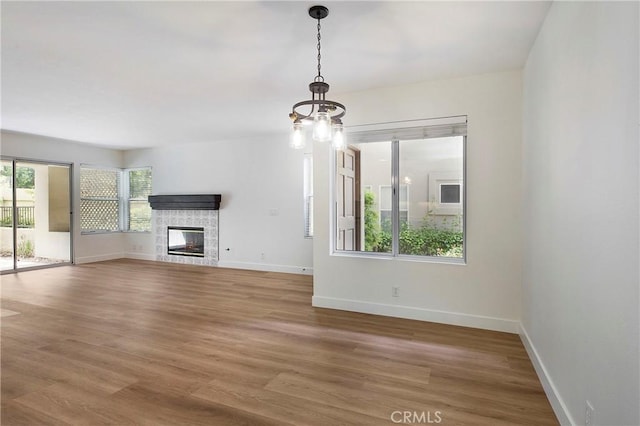 unfurnished living room featuring baseboards, light wood finished floors, and a glass covered fireplace
