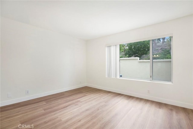 unfurnished room featuring baseboards and light wood-style flooring