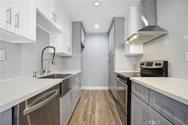 5414 Newcastle Ave Unit 66, Encino, CA 91316 - kitchen with wall chimney exhaust hood, stainless steel appliances, a sink, light wood-style floors, and gray cabinetry