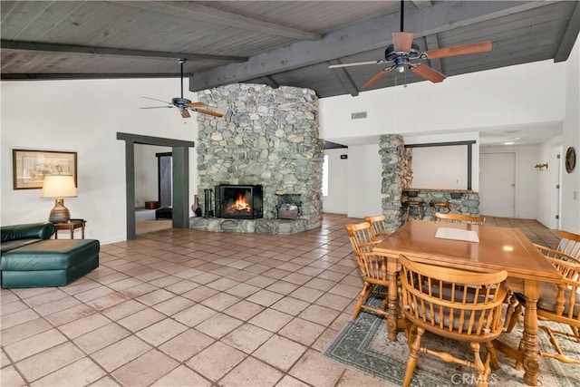 dining space with a fireplace, high vaulted ceiling, a ceiling fan, beamed ceiling, and visible vents