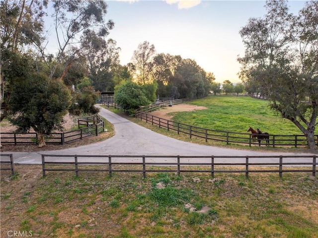 view of property's community with a lawn, a rural view, fence, and an enclosed area