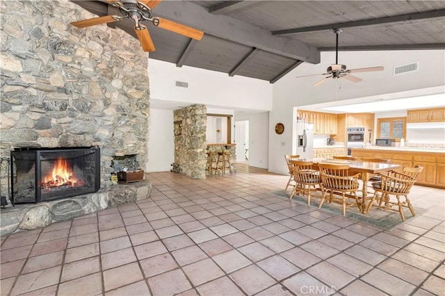 dining space featuring a ceiling fan, a stone fireplace, and visible vents